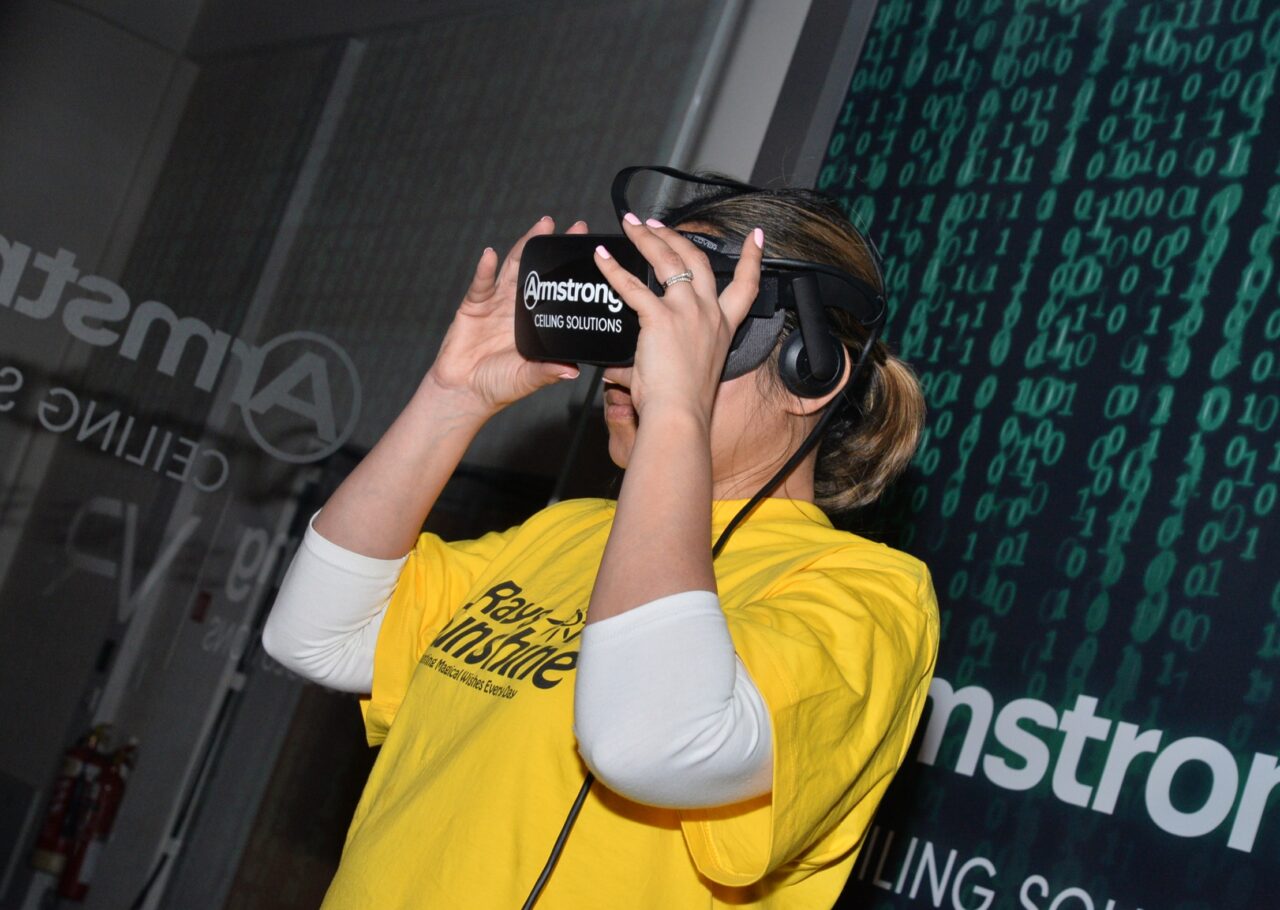 A woman in a yellow t-shirt is using a virtual reality headset