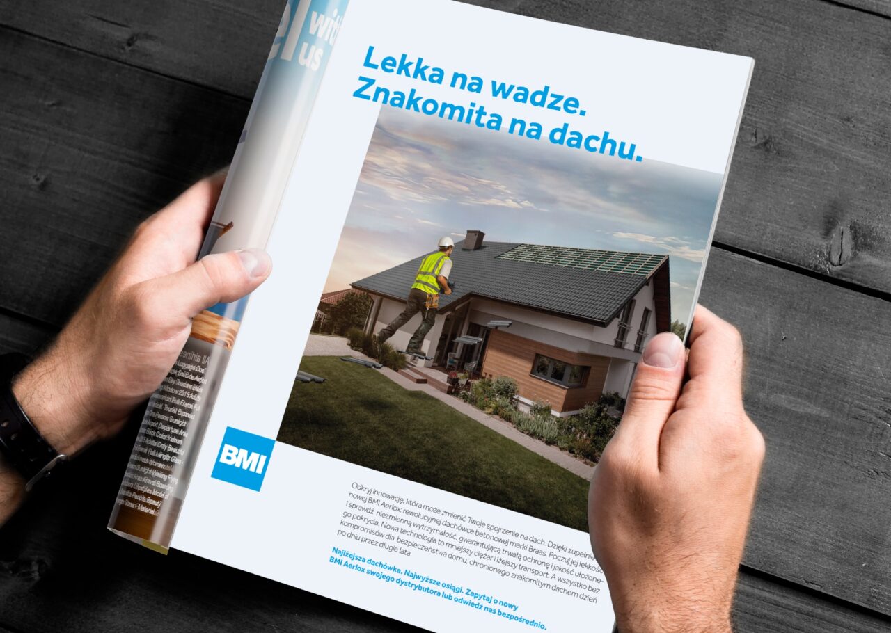 A close up shot of a pair of hands holding a book featuring an article from BMI, talking about roofing, translated into Polish