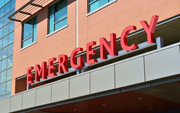 A low angle, exterior shot of a hospital emergency ward sign