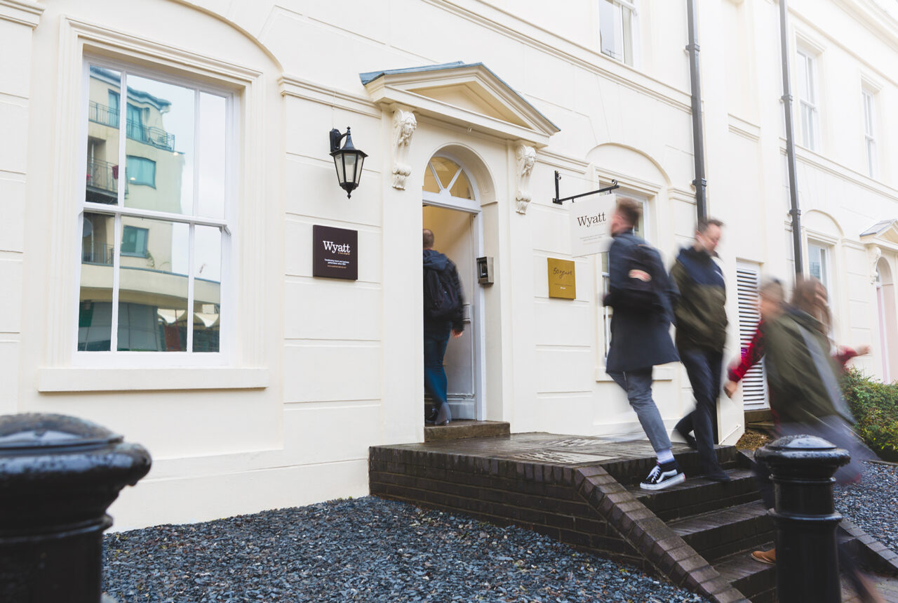 An exterior shot of the wyatt international office, whilst blurred people are walking in and out