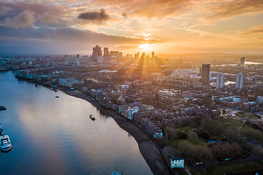 A wide landscape shot of a city skyline, river and suburbs