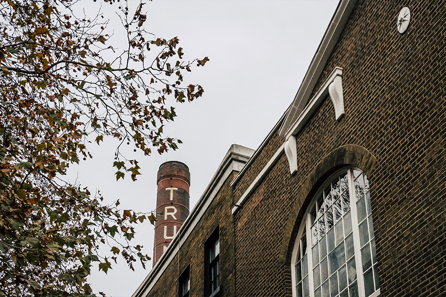 An upwards facing photograph of a brownstone building exterior, with a chimney in the background and tree in the midground.