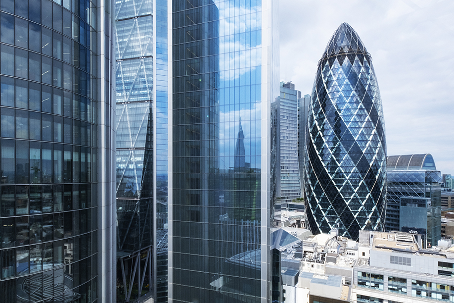 A wide landscape shot of the gherkin building in London, with other skyscrapers surrounding it