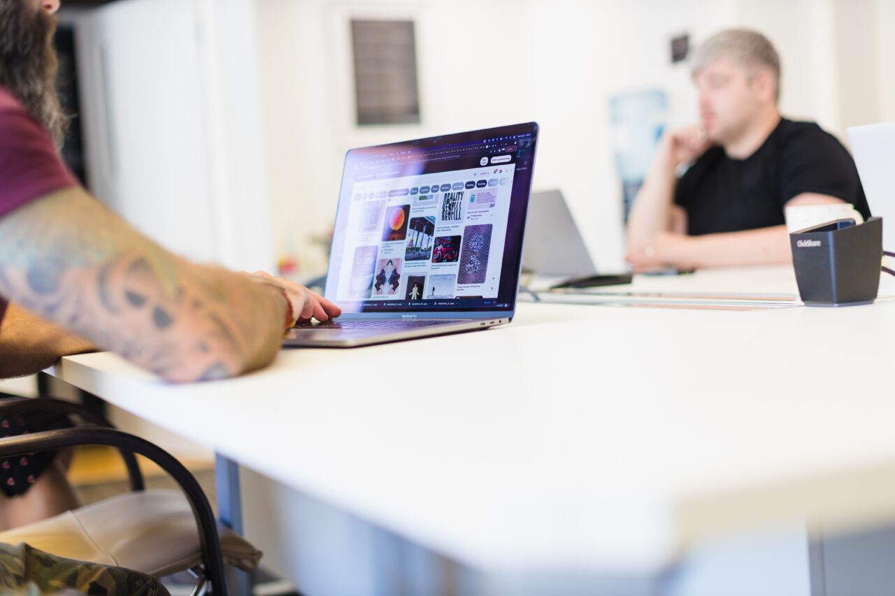 A shot of two colleagues in a meeting, with a laptop in the foreground showing design examples.