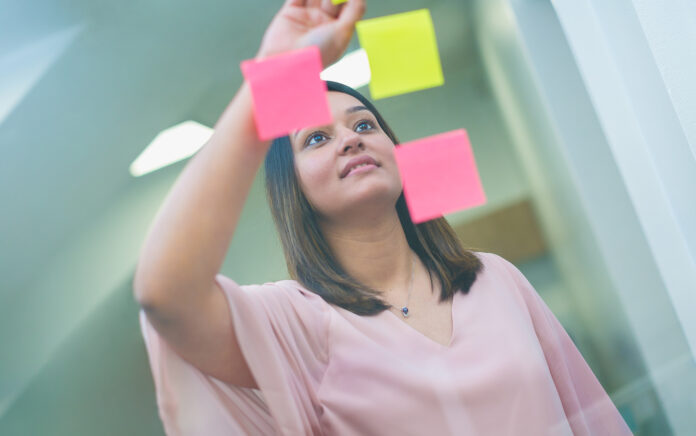 A female office worker pasting sticky notes on a window