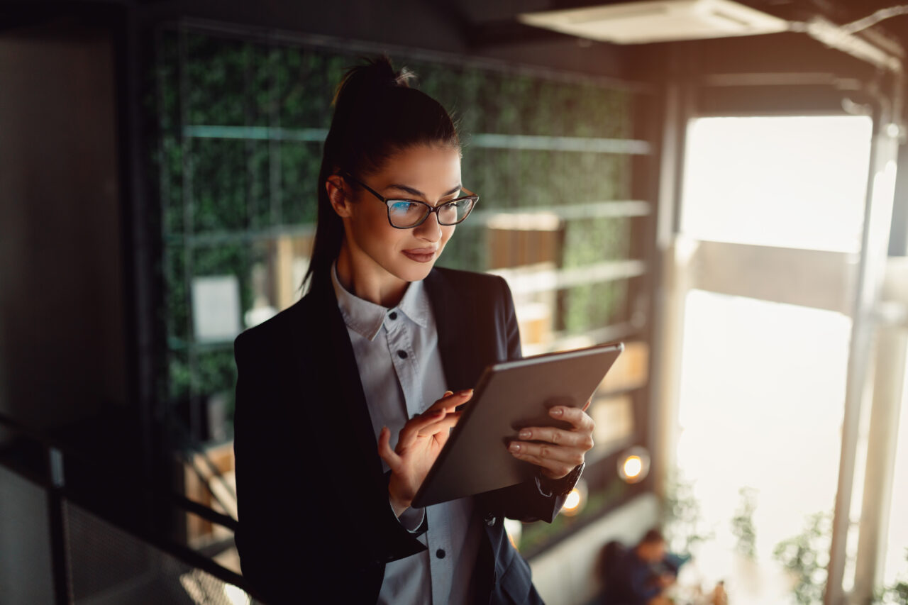 Female office worker standing on an office balcony holding an electronic tablet