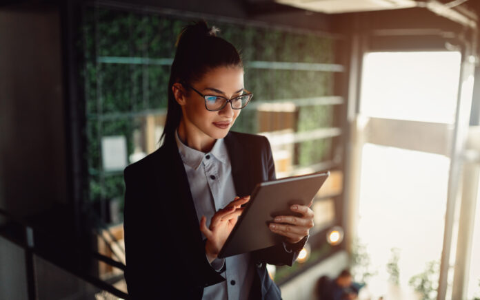 Female office worker standing on an office balcony holding an electronic tablet