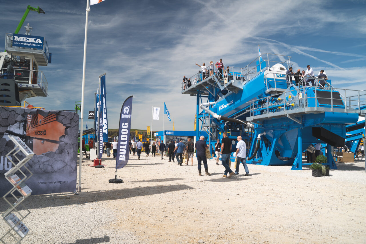 An image of a construction equipment at an event, with a crowd walking through a quarry.