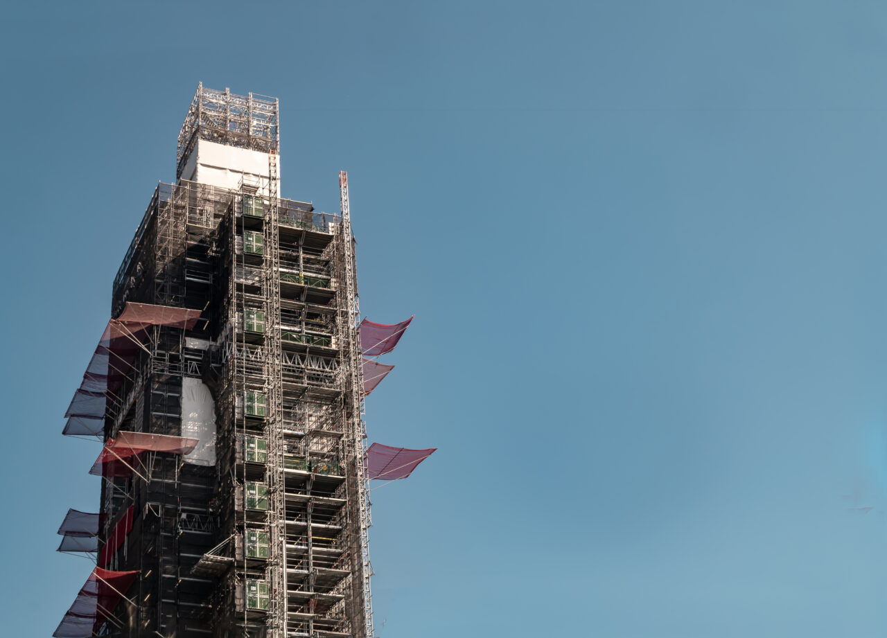 A zoomed in shot of the top of a building that is being constructed with scaffolding all over it