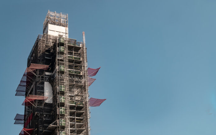 A zoomed in shot of the top of a building that is being constructed with scaffolding all over it