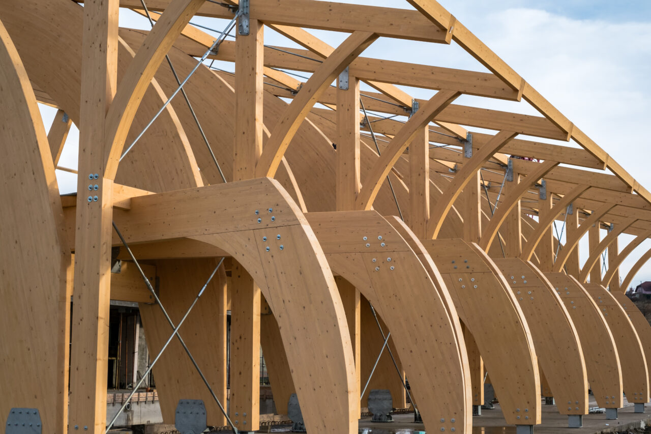 Detail of a modern wooden architecture in glued laminated timber on a blue cloudy sky.