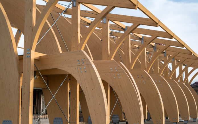 Detail of a modern wooden architecture in glued laminated timber on a blue cloudy sky.