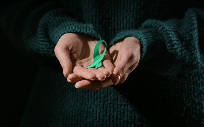 A close up shot of a pair of hands holding a ribbon to symbolise Mitochondrial diseases and kidney cancer