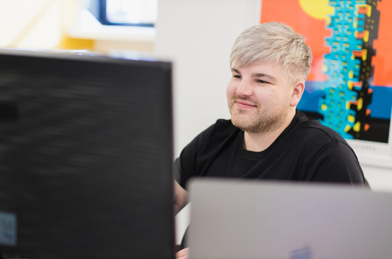 Ben Baker-Holyhead, Strategic Account Director at Wyatt International, working on a computer and smiling.