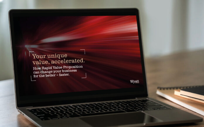 An image of a laptop on a desk with notebooks beside. The laptop is displaying the text 'Your unique value, accelerated. How Rapid Value Proposition can change your business for the better'.