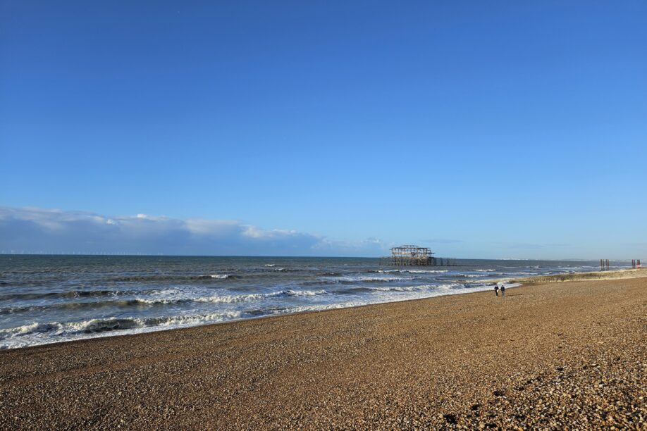 Brighton beach with opean sea, clouds in the background and burnt down pier