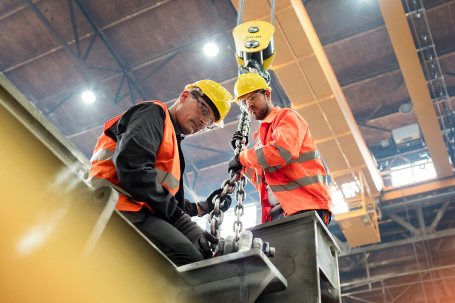 Two construction workers in high vis jackets are engaged in operating a crane, ensuring safety and precision.
